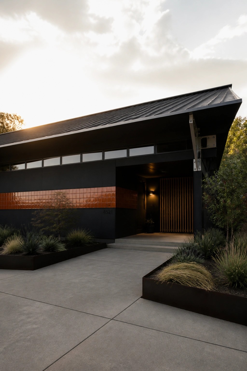 Modern dark house with orange tiles, metal roof, concrete steps, and garden landscaping.