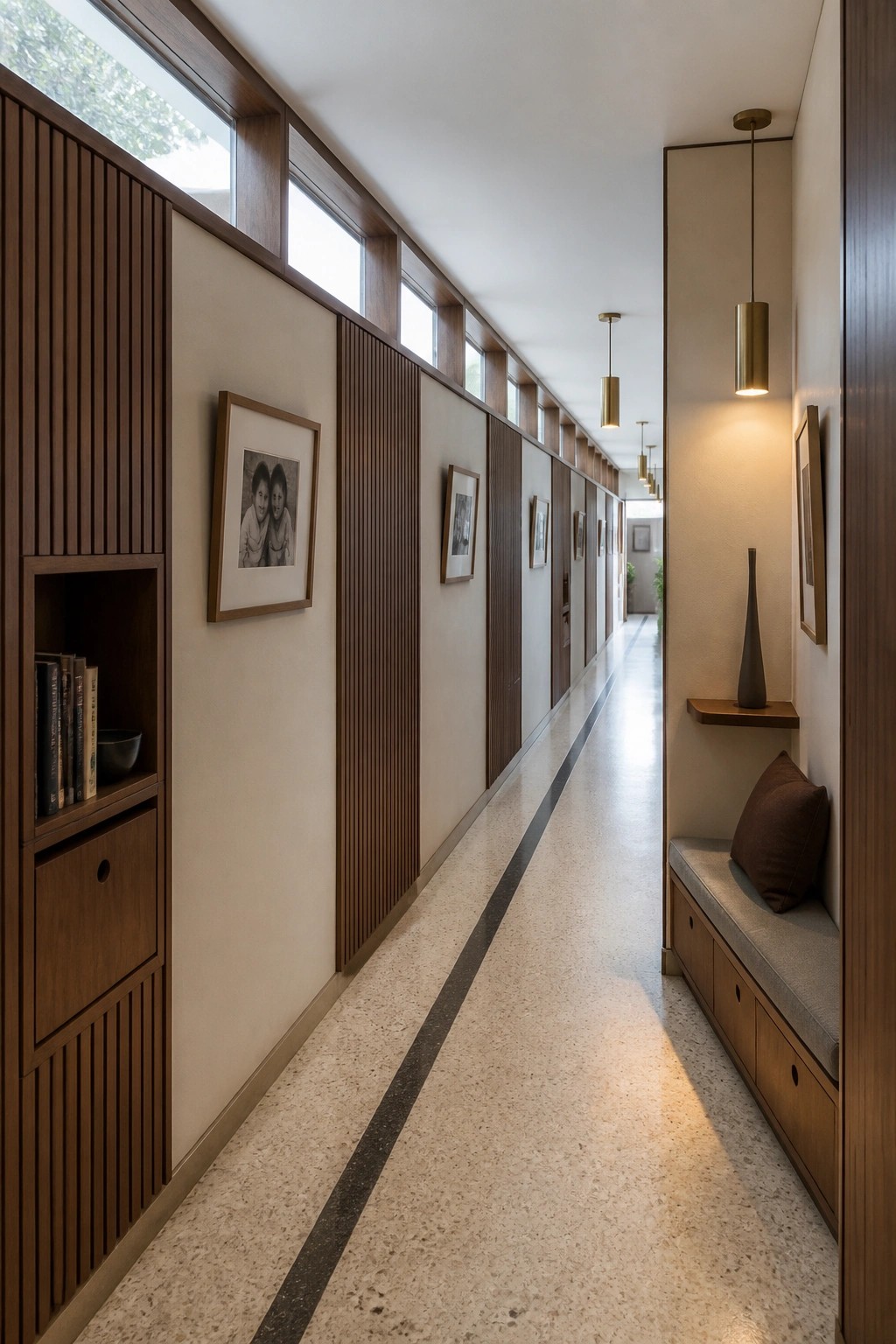 Long narrow interior hallway with built-in wooden bookshelves on the left wall, a cushioned bench with drawers on the right, and pendant lights overhead.