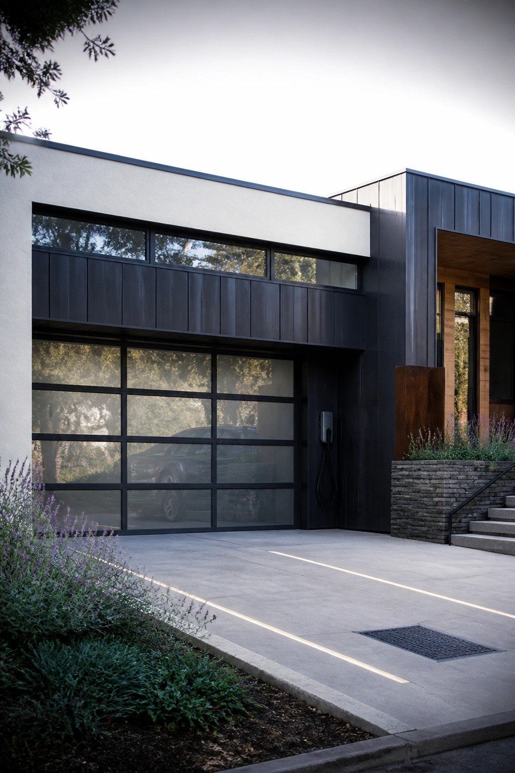 Modern house exterior with a black-framed glass garage door and a wall-mounted EV charger positioned to the right of the door.