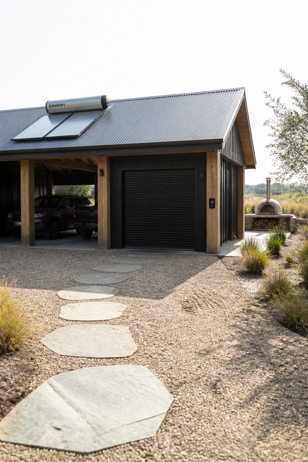 Modern garage with solar panels, black truck in carport, stone path to pizza oven.