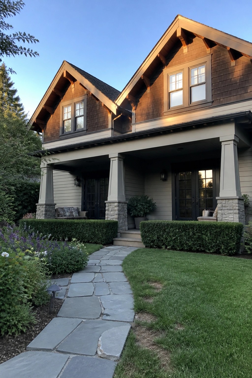 Two-story house with dark wood siding, stone porch pillars, and flagstone path at dusk
