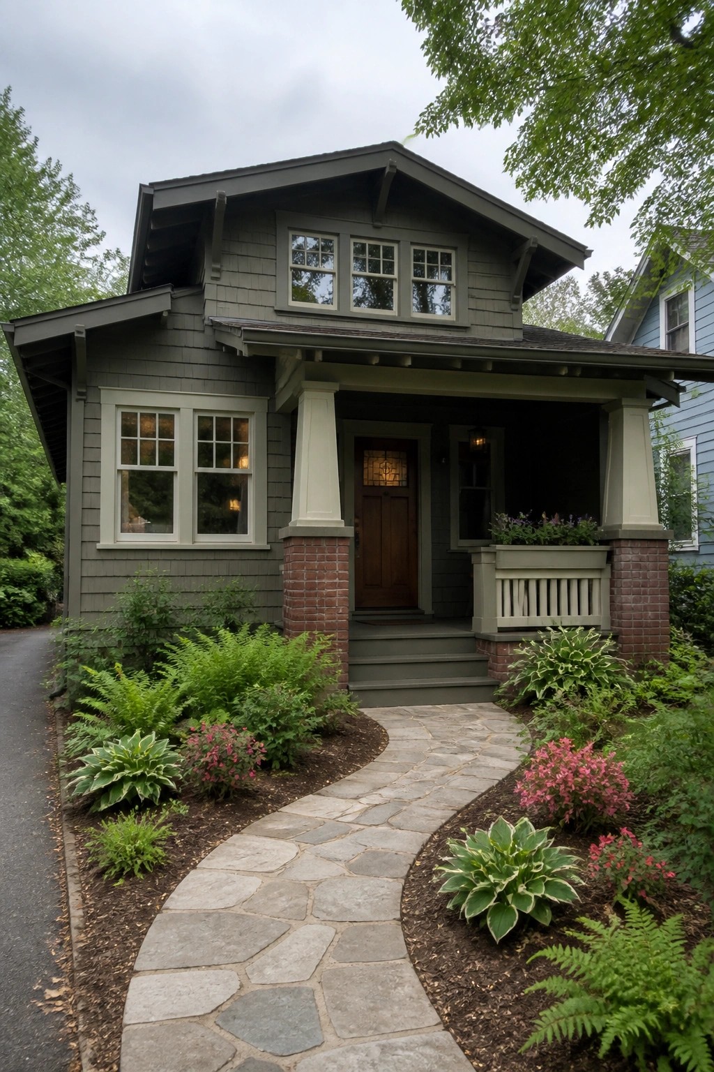 Gray Craftsman bungalow with porch, wooden door, stone path, and lush garden.