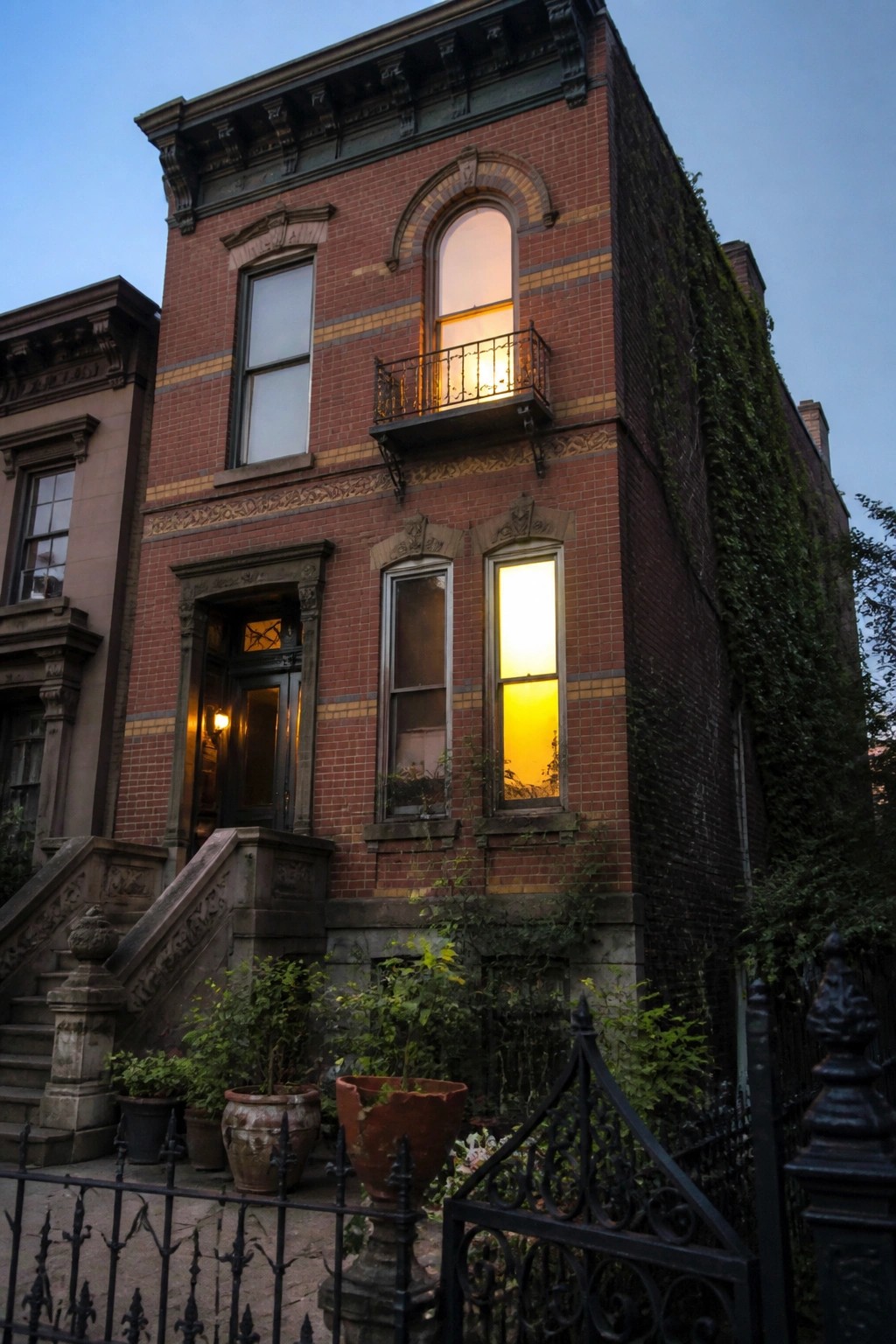 Yellow mansion with cupola, arched doorway, tall evergreens, and formal boxwood garden.