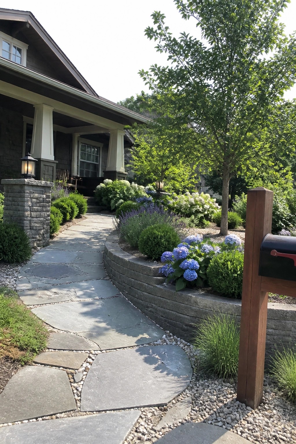 Stone path curves past blue hydrangeas toward house porch with mailbox nearby.