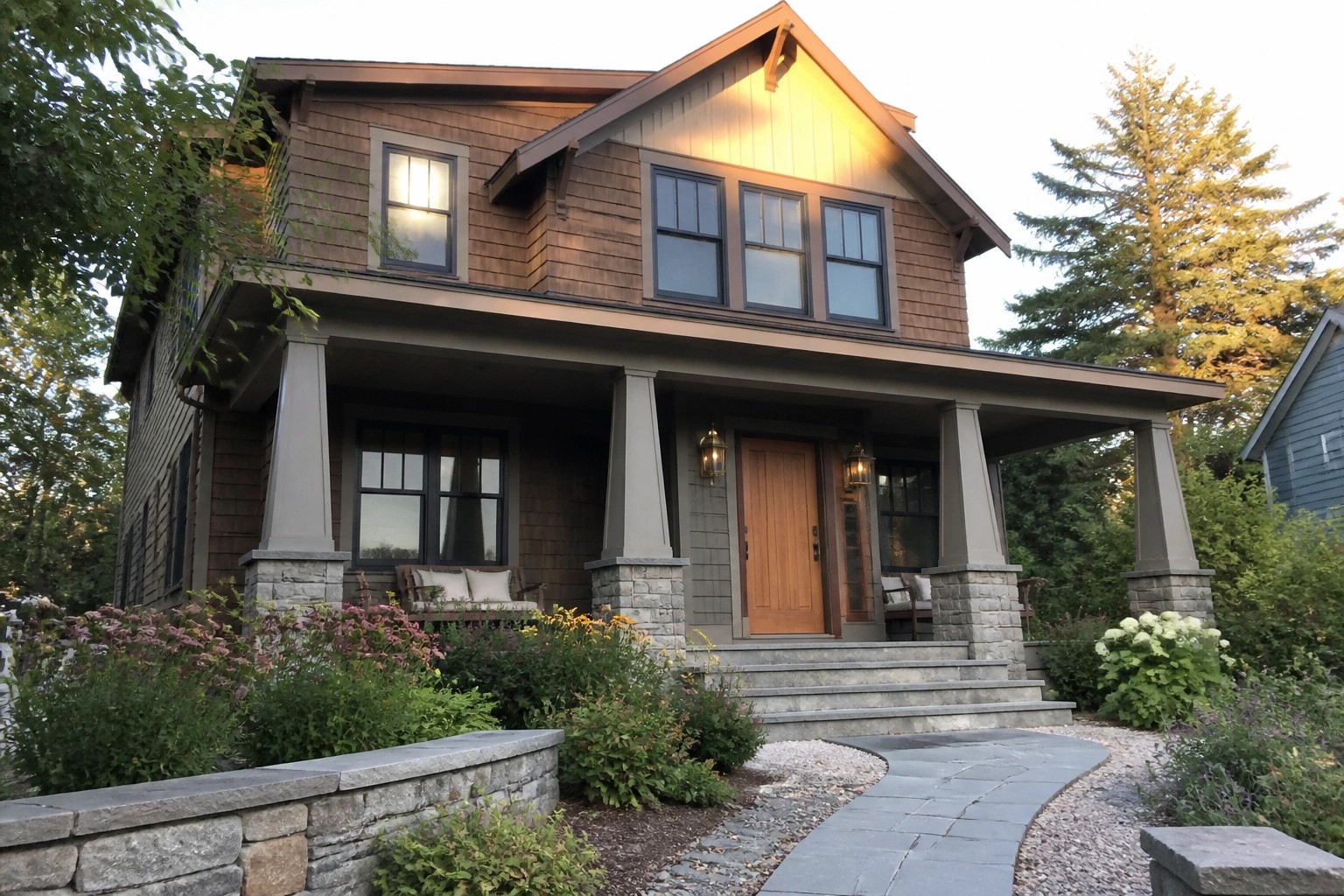 Two-story wooden house with porch, stone path, and blooming flower garden.
