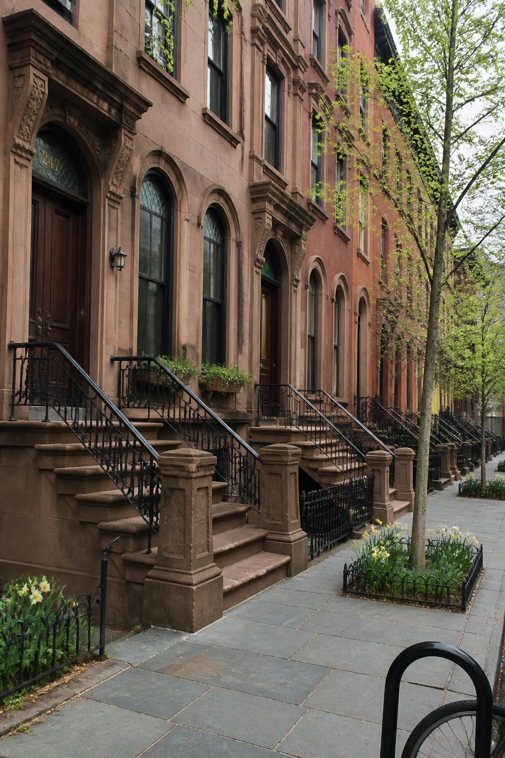 Ornate red brick mansion with mansard roof, stone trim, and formal hedge garden.