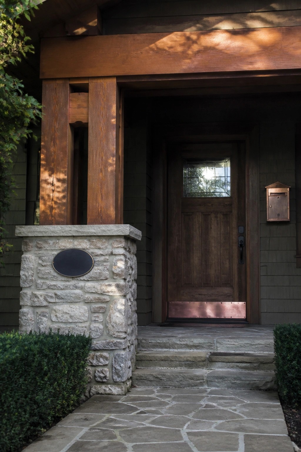 Wooden door with copper accents beside stone pillar at house entrance